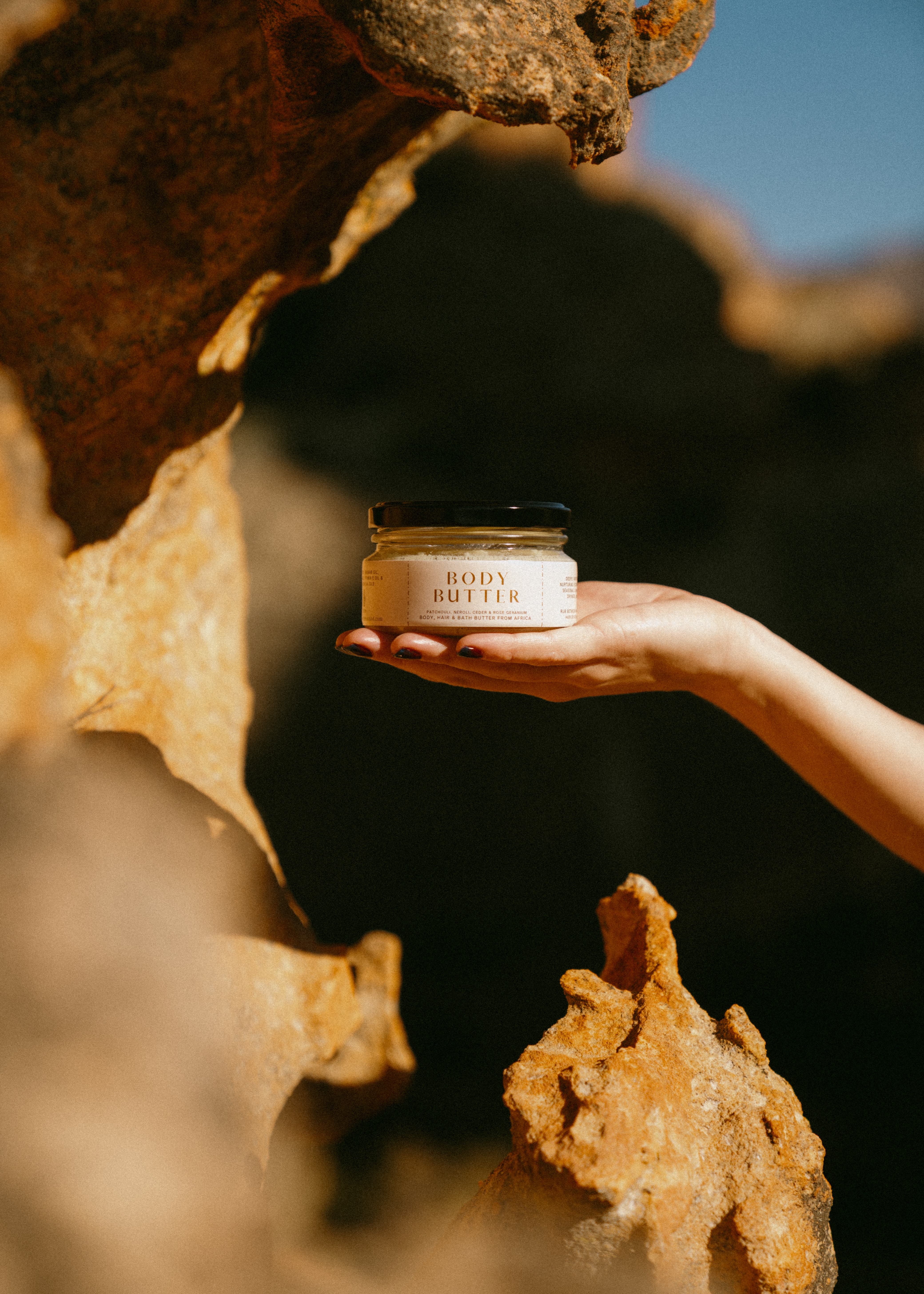 Body Butter by NUNA held among warm stone.