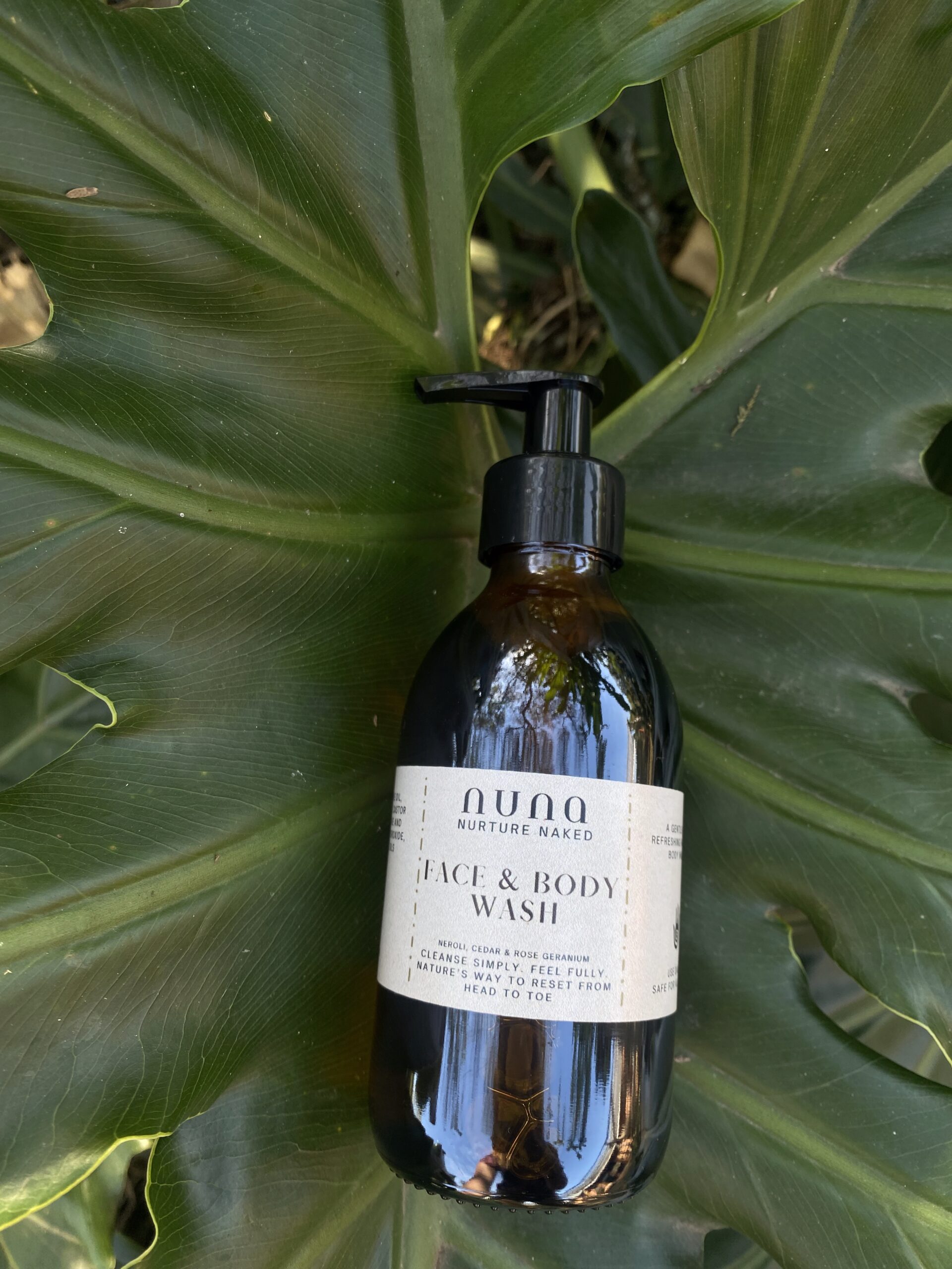 Face & Body Wash by NUNA resting on a green leaf.